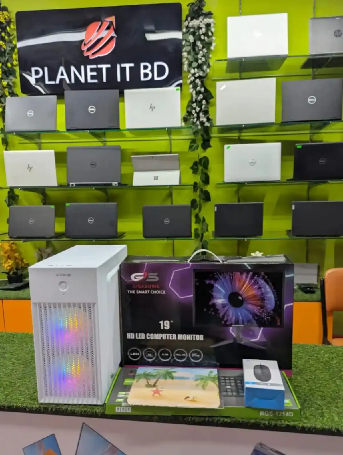 High-quality laptops and gaming monitors displayed on a vibrant green wall at Planet IT BD store, showcasing a wide selection of technology products for consumers.
